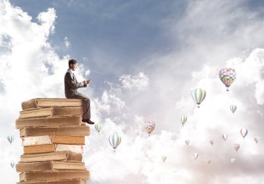 Yığın kitap üzerinde oturan işadamı 
