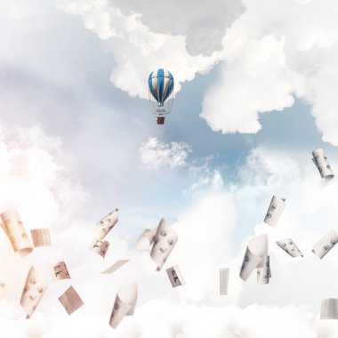 Renkli aerostat kağıt belgeler arasında ve mavi bulutlu gökyüzü üzerinde uçan. 