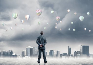 Arka ayakta ve havada uçan aerostats bakarak bir işadamı