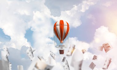 Renkli aerostat kağıt belgeler arasında ve mavi bulutlu gökyüzü üzerinde uçan. 