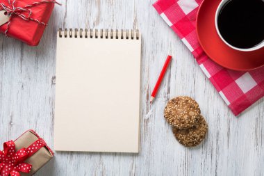 Tarif defteri kahve fincanı ve kurabiyeler ahşap masanın üstünde.