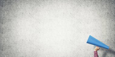 El kağıt trompet beton arka planda tutan kadın