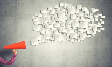 Beton arka planda kırmızı borazan tutan bir kadın eli