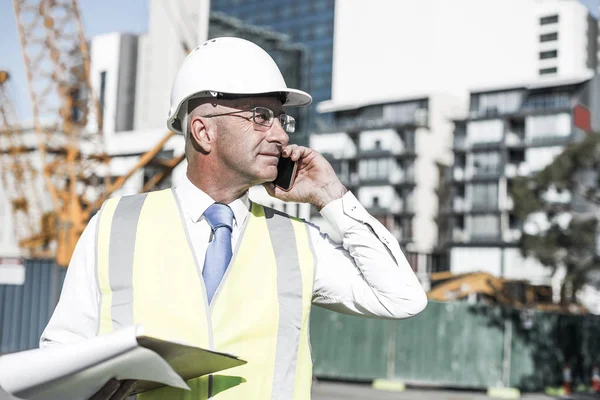 Senior engineer man in suit and helmet talking mobile phone