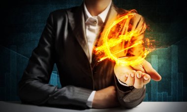 İşadamı ile koyu arka plan elinde yanan euro işareti gösteren takım elbiseli Close-Up.