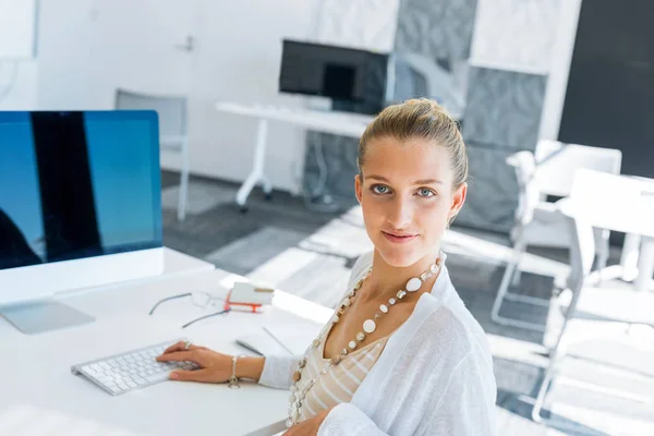 Masada Oturan Bilgisayarda Çalışarak Çekici Genç Kadın — Stok fotoğraf