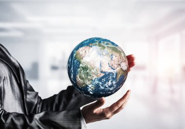 İş kadını dünya küre zemin üzerine güneş ışığı ve office manzaralı elinde tutan takım elbiseli kırpılmış görüntü. Bu görüntü unsurları Nasa tarafından döşenmiştir.