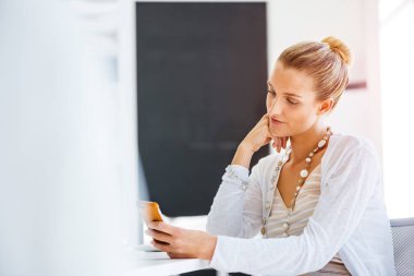 Masada oturan ve cep telefonuyla çekici genç kadın