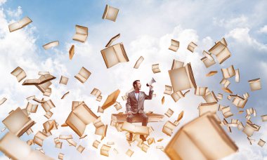 kitap üzerinde oturan genç işadamı
