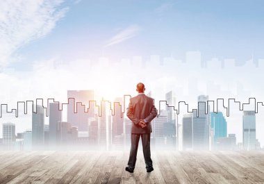 İşadamı arkasını dönüp modern iş merkezinin siluetine bakıyor.