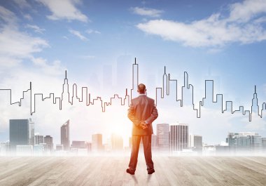 İşadamı arkasını dönüp modern iş merkezinin siluetine bakıyor.