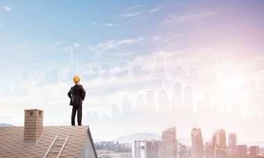 takım elbise ve kask çatıda işadamı