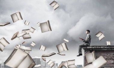 Elinde kırmızı kitap ile kenar binasında oturan genç işadamı