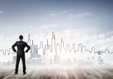 İşadamı arkasını dönüp modern iş merkezinin siluetine bakıyor.