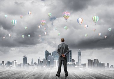 Arka ayakta ve havada uçan aerostats bakarak bir işadamı