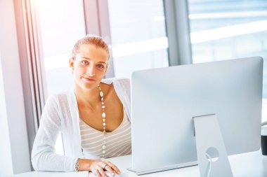 Masada oturan ve bilgisayarda çalışarak çekici genç kadın