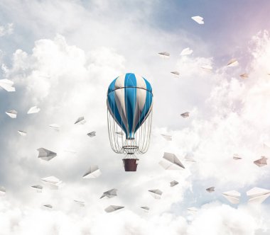 Renkli aerostat kağıt uçaklar arasında ve mavi bulutlu gökyüzü üzerinde uçan. 