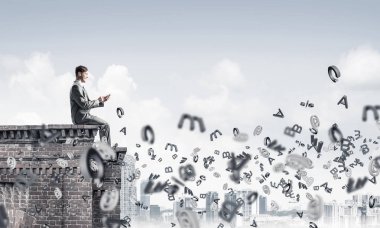 Elinde smartphone ile üst yapı üzerinde oturan genç işadamı