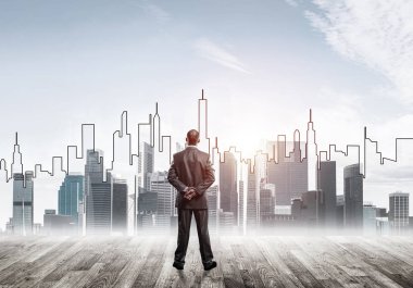 İşadamı arkasını dönüp modern iş merkezinin siluetine bakıyor.