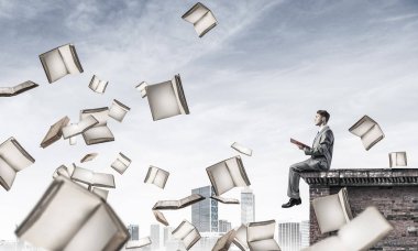 Elinde kırmızı kitap ile kenar binasında oturan genç işadamı