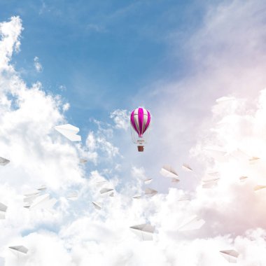 Renkli aerostat kağıt uçaklar arasında ve mavi bulutlu gökyüzü üzerinde uçan. 