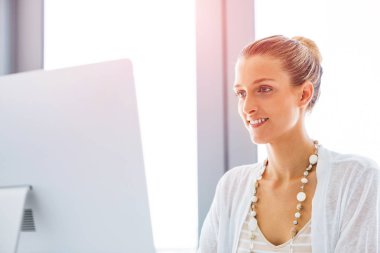 Masada oturan ve bilgisayarda çalışarak çekici genç kadın