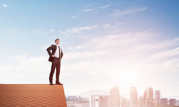 Businessman standing on house roof