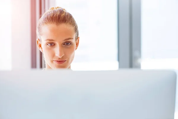 Attractive young woman sitting at desk and working on computer