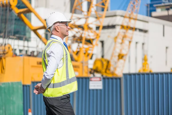 Homem que controla o local de construção exterior — Fotografia de Stock