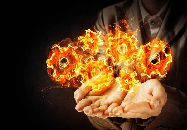 Businessman Suit Presenting Flaming Cogwheels Structure His Hands Dark Wall — Stock Photo, Image