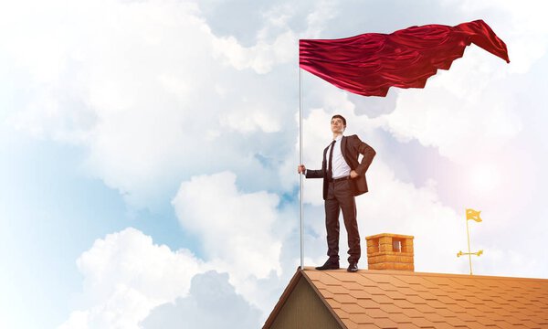 Businessman standing on house roof