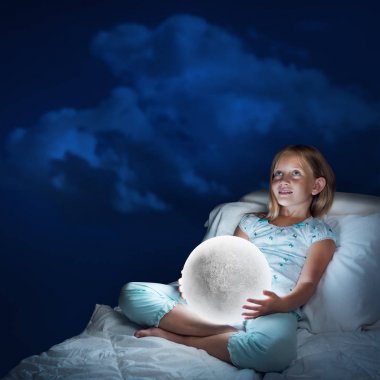 Sevimli kız ay gezegen ile yatakta oturuyor