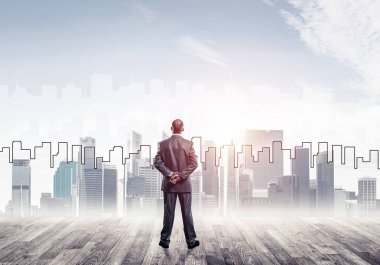 İşadamı arkasını dönüp modern iş merkezinin siluetine bakıyor.