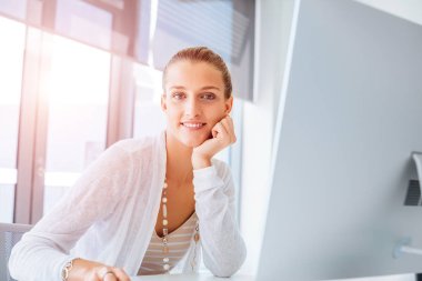 Masada oturan ve bilgisayarda çalışarak çekici genç kadın