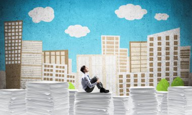 Düşünceli işadamı uzakta ile arka plan üzerinde çizilmiş cityscape belgeleri yığını üzerinde otururken arıyorum. Karışık teknik.