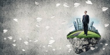 Yeşil yüzen adada beton zemine karşı duran kendine güvenen zarif iş adamı.