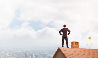 evin çatısında duran işadamı 