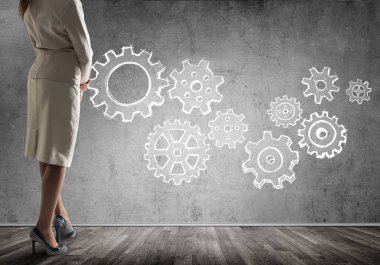 Duvarın önünde çekilmiş vites mekanizması, ekip çalışması kavramı ile ayakta işkadını alttan görünüm 