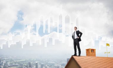 evin çatısında duran işadamı 