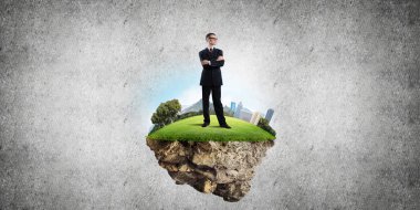 Yeşil yüzen adada beton zemine karşı duran kendine güvenen zarif iş adamı.