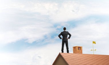 evin çatısında duran işadamı 