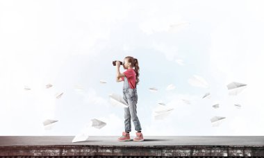 Dürbünle bakan, okul çağındaki sevimli kız çatıyı inşa ediyor.