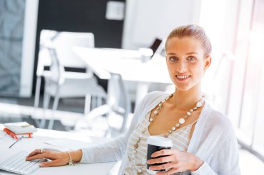 Masada oturan ve bilgisayarda çalışarak çekici genç kadın
