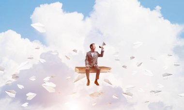kitap üzerinde oturan genç işadamı