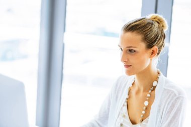 Masada oturan ve bilgisayarda çalışarak çekici genç kadın