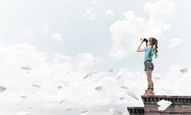 Dürbünle bakan, okul çağındaki sevimli kız çatıyı inşa ediyor.