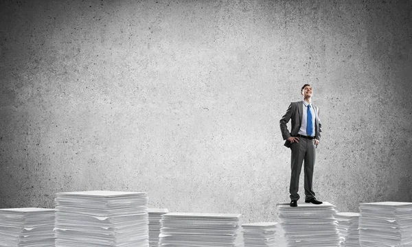 Businessman in suit standing on pile of documents — Stock Photo, Image