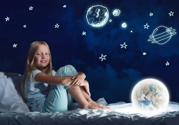 Cute girl sitting in bed with Earth planet