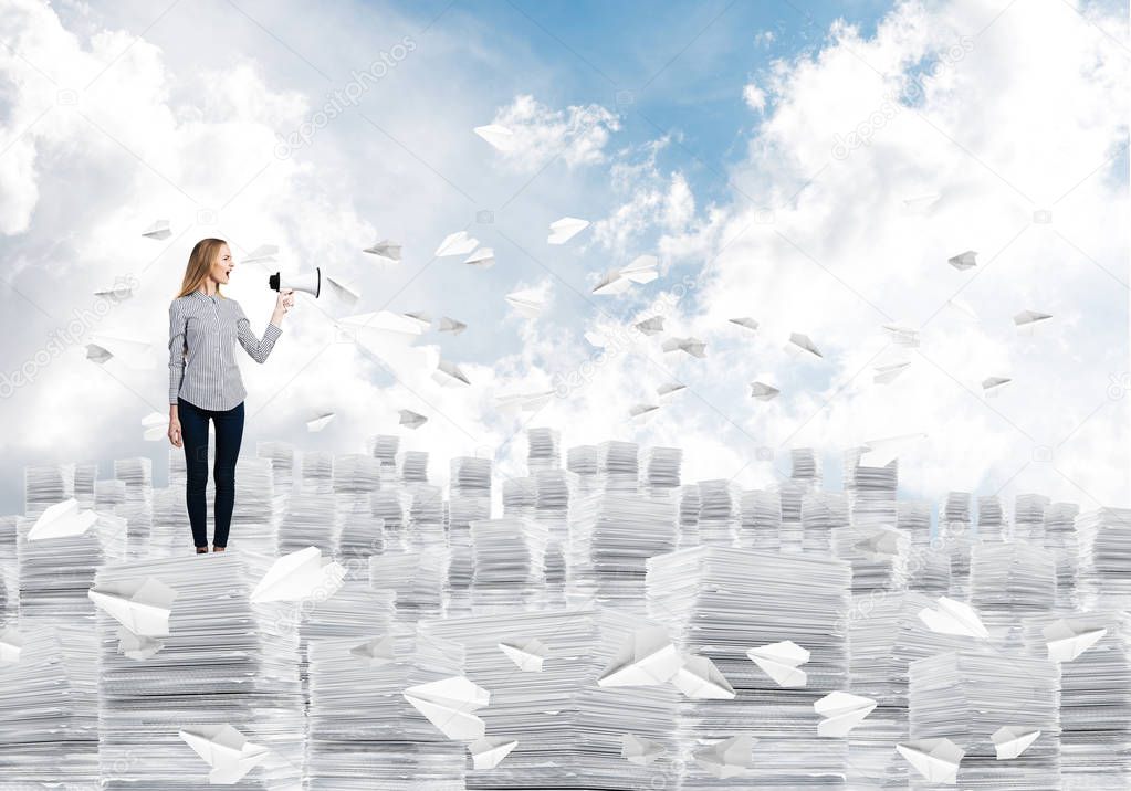 Woman in casual clothing standing on pile of documents among flying paper planes with speaker in hand with cloudly skyscape on background. Mixed media.