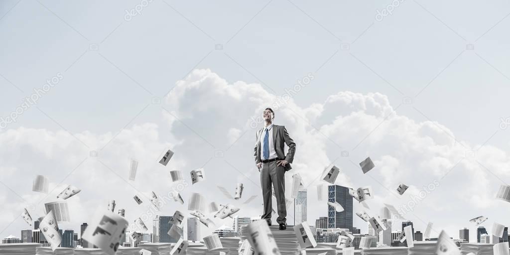 Businessman in suit standing on pile of documents